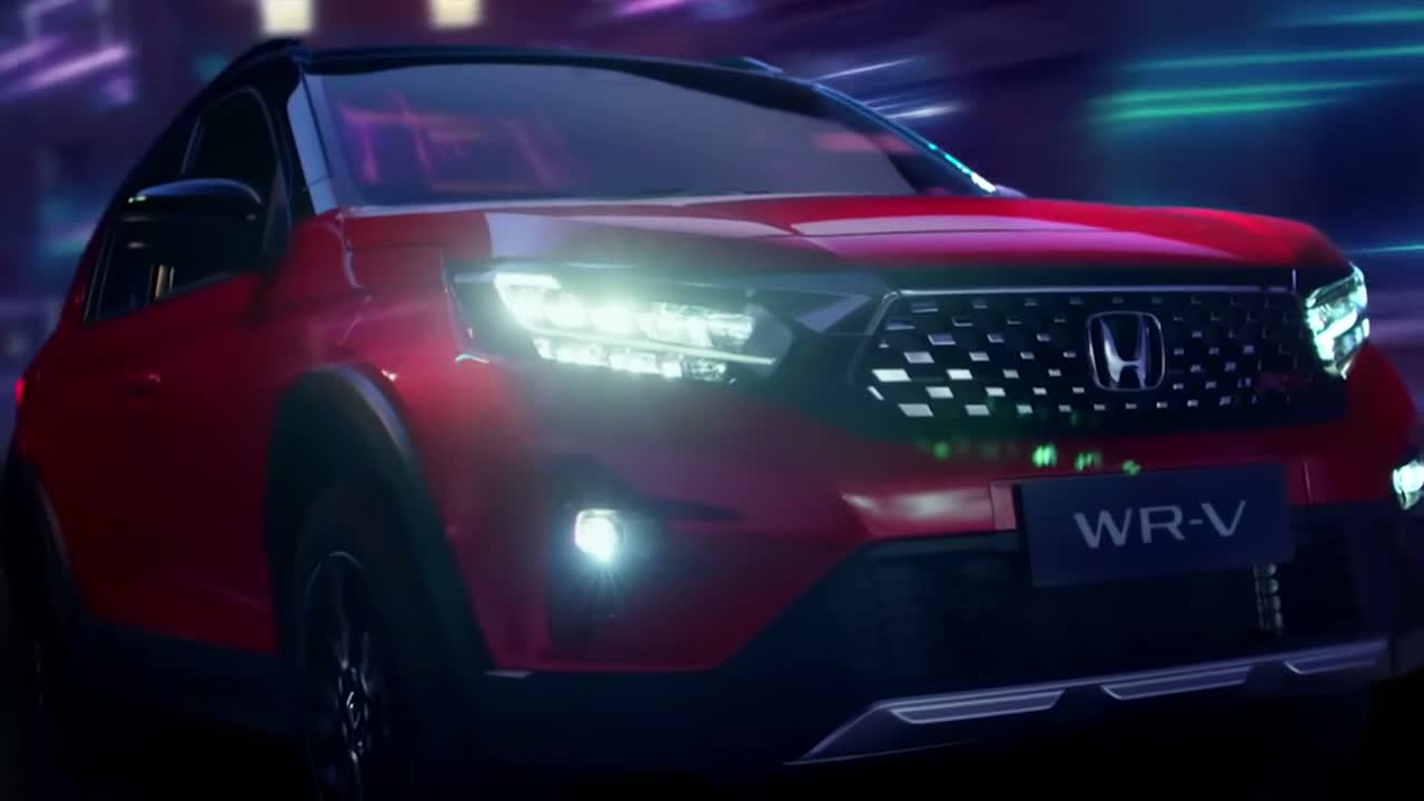 A red Honda WR-V, headlights lit, shot at night with neon reflections, from the WR-V launch film.